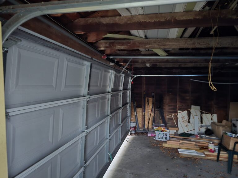Garage door with damaged panels and hinges before repair