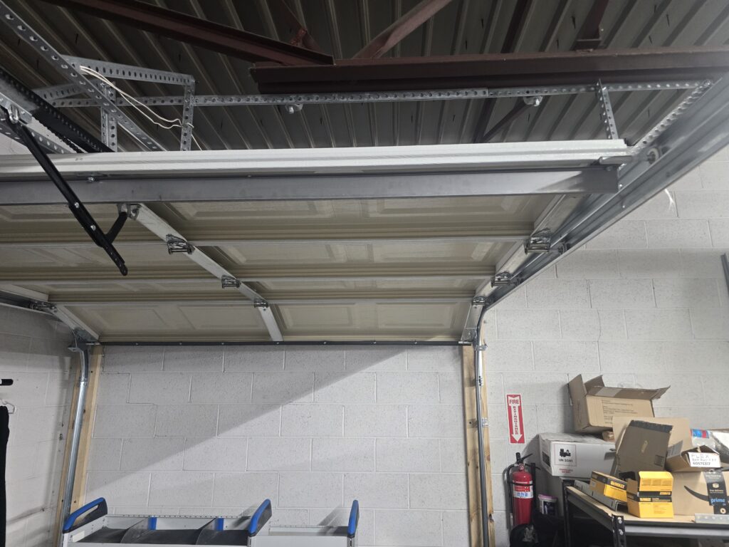 Garage door tracks and an opener rail set up in the Proactive Garage Door Repair shop