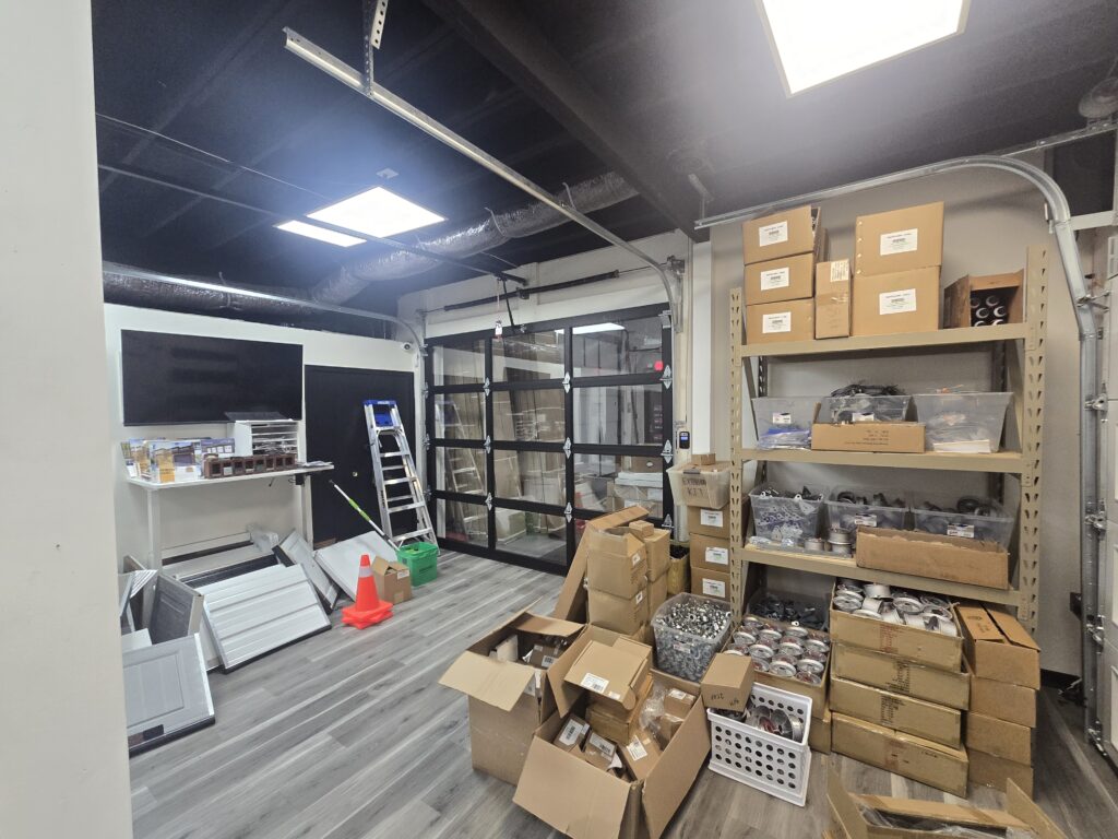 Display garage doors with glass panels next to stocked parts at Proactive