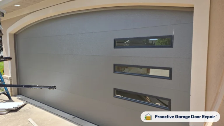Gray modern flush garage door with three long windows installed by Proactive Garage Door Repair